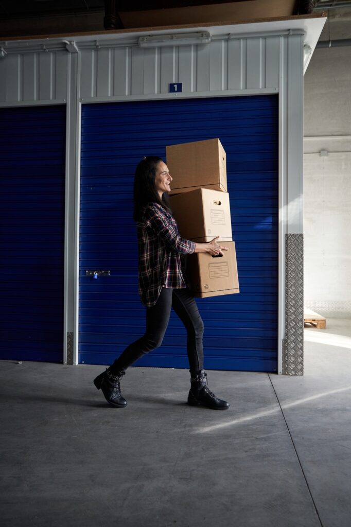 Woman carrying packing boxes near storage